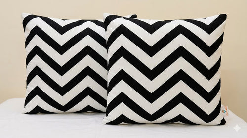 Two black and white chevron patterned pillows on a light-colored surface.
