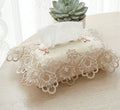 Lace-patterned tissue box cover on a table with a succulent plant in the background