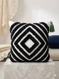 Decorative pillow with black and white geometric pattern on a marble surface.