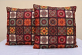 Two decorative pillows with a patchwork pattern on a white surface.