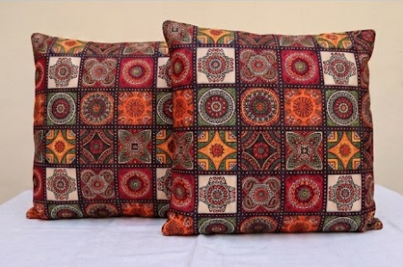 Two decorative pillows with a patchwork pattern on a white surface.