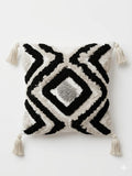 Decorative pillow with black and white geometric pattern and tassels on a white background