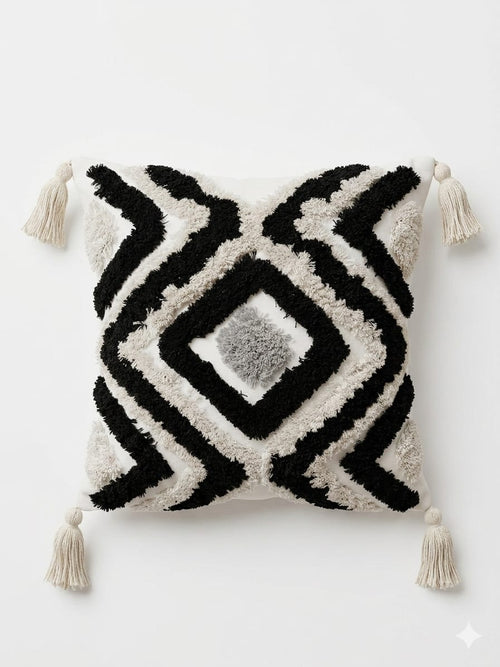 Decorative pillow with black and white geometric pattern and tassels on a white background