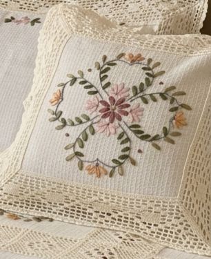 Embroidered pillow with floral design on a textured fabric background