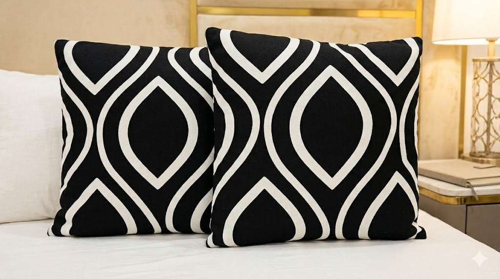 Two black and white patterned pillows on a bed.