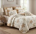 Floral patterned bedding set on a bed in a bedroom with a lamp and side table.