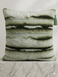 Textured green pillow with a tassel on a marble surface