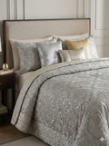 Silver patterned comforter set on a bed with matching pillows in a bedroom setting.