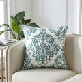 Decorative pillow with green leaf pattern on a beige sofa in a bright room.