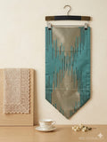 Decorative fabric with geometric pattern on a hanger against a beige wall.