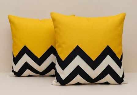Two yellow pillows with black and white zigzag patterns on a neutral background